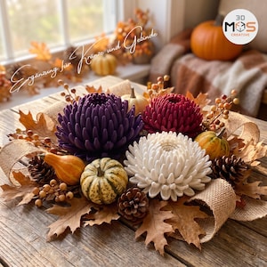 Op de afbeelding: Een decoratief herfststuk met drie grote chrysanten in paars, donkerrood en wit. Het arrangement bevat kleine gestreepte kalebassen, bruine dennenappels, gedroogde eikenbladeren en accenten van beige jute lint.