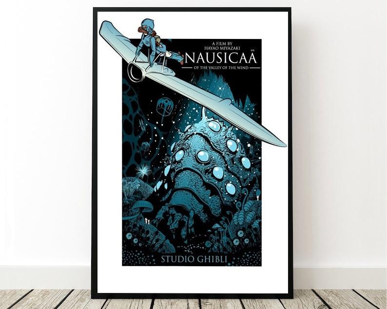 May include: Framed poster for "Nausica&auml; of the Valley of the Wind", featuring a character on a glider above a blue, glowing landscape. The poster includes the film title and "Studio Ghibli" text. The artwork is in a black frame.
