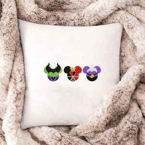 Peut inclure: Coussin carr&eacute; blanc avec des motifs brod&eacute;s de trois visages de personnages de dessins anim&eacute;s. Les motifs pr&eacute;sentent des couleurs noires, vertes, violettes, rouges et jaunes. Le coussin est pos&eacute; sur une couverture en fausse fourrure.