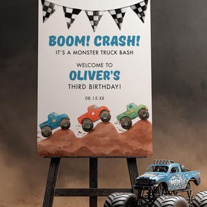 May include: A sign on an easel with the text "BOOM! CRASH! IT'S A MONSTER TRUCK BASH. WELCOME TO OLIVER'S THIRD BIRTHDAY!" and three monster truck illustrations. A blue monster truck is in the foreground.