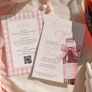 May include: Two rectangular baby shower invitation cards with pink and white gingham borders. The cards feature text including "She's ready to Pop!", "Details", "Diaper Raffle", "Books for Baby", and "Registry" with a QR code and event information.