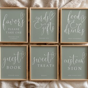 May include: Six framed signs with a sage green background and wooden frames. Each sign has white cursive text with a heart design. The signs read: "Favors, Cards & Gifts, Food & Drinks, Guest Book, Sweet Treats, and Custom Sign."