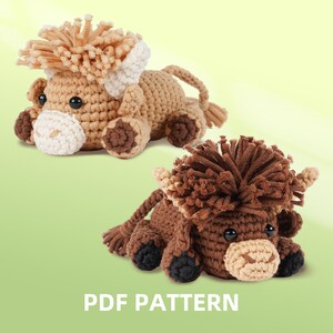 Op de afbeelding: Twee gehaakte Highland koeien knuffels in bruin- en beigetinten, met harige manen en kleine hoorns. De koeien hebben zwarte ogen en liggen. De tekst "PDF PATTERN" staat onderaan.