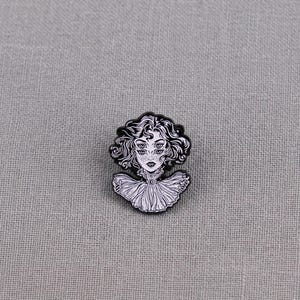 Könnte beinhalten: Ein schwarz-weißer Emaille-Pin mit einer stilisierten Illustration einer Frau mit vier Augen und lockigem Haar. Der Pin hat ein detailliertes Design eines Rüschenkragens und ist vor einem grauen Hintergrund platziert.