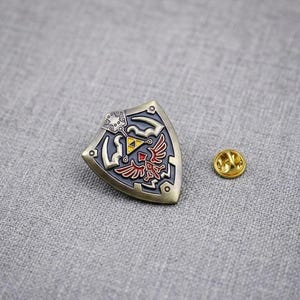 Emaljnål med fantasisköld, spelbrosch i antik brons, hattnål med gyllene triangel-emblem