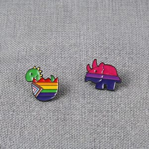 Pode incluir: Dois pinos de esmalte sobre uma superfície cinza. Um pino é um dinossauro verde saindo de um ovo arco-íris. O outro pino é um rinoceronte rosa e roxo. Ambos os pinos têm um contorno preto.