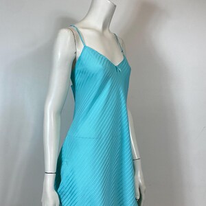 K&ouml;nnte beinhalten: Ein hellblaues Satin-Schlafkleid mit d&uuml;nnen Tr&auml;gern und einer zarten Schleife am Ausschnitt.