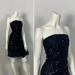 May include: A black strapless mini dress with a sequined bodice and a black satin bow at the waist.