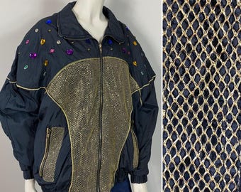 May include: A black and gold jacket with a mesh panel and rhinestone embellishments. The jacket has a zipper closure and two pockets.
