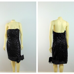 May include: A black strapless sequined dress with a satin bow on the side. The dress is knee-length and has a fitted silhouette.