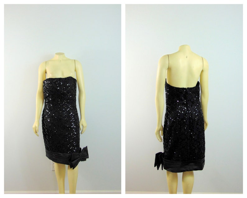 May include: A black strapless sequined dress with a satin bow on the side. The dress is knee-length and has a fitted silhouette.