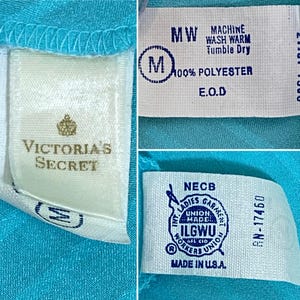 K&ouml;nnte beinhalten: Ein t&uuml;rkisblaues Satin-Oberteil mit einem wei&szlig;en Etikett, auf dem "Victoria's Secret" steht, und einem wei&szlig;en Etikett mit Pflegehinweisen, auf dem "Machine Wash Warm, Tumble Dry, 100% Polyester, E.O.D." steht.