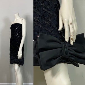 May include: A black sequined strapless dress with a black satin bow clutch.