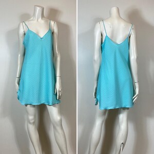 K&ouml;nnte beinhalten: Ein hellblaues, &auml;rmelloses Schlupfkleid mit einem d&uuml;nnen, horizontalen Streifenmuster. Das Kleid hat einen V-Ausschnitt und eine leicht A-f&ouml;rmige Silhouette.