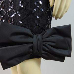May include: A black sequined skirt with a large black satin bow at the hem.