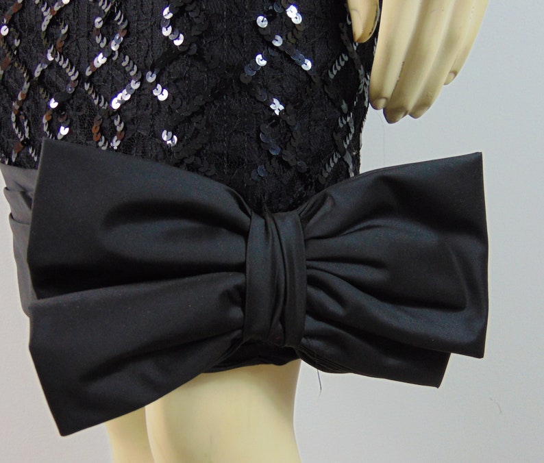 May include: A black sequined skirt with a large black satin bow at the hem.