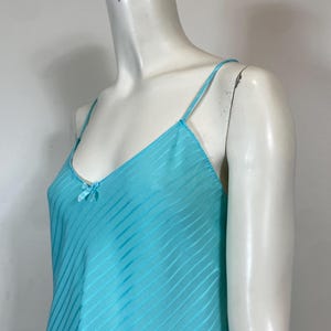 K&ouml;nnte beinhalten: Ein hellblaues, &auml;rmelloses, seidenes Schlupfkleid mit d&uuml;nnen Tr&auml;gern und einer Schleife am Ausschnitt.