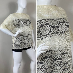 May include: A white lace top with a boat neck and short sleeves. The lace has a floral pattern and is semi-sheer.