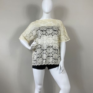 May include: A white lace top with a loose fit and short sleeves. The top is sheer and has a floral pattern.