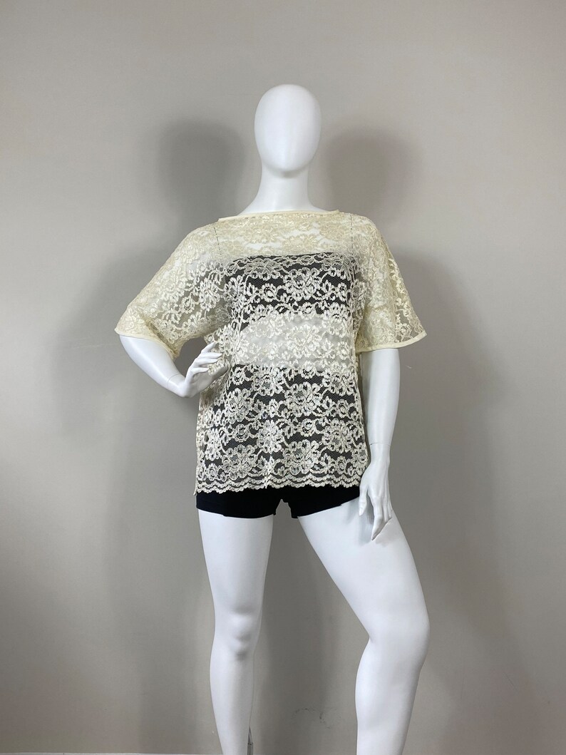 May include: A white lace top with a loose fit and short sleeves. The top is sheer and has a floral pattern.