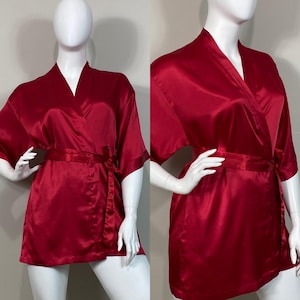 Puede incluir: Una bata de satén roja con cierre de envoltura y un lazo de cinta. La bata tiene mangas cortas y cuello en V.