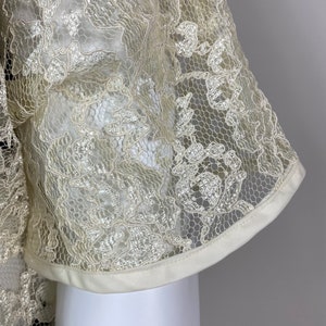 May include: Close-up of a white lace fabric with a floral pattern. The fabric has a satin trim.