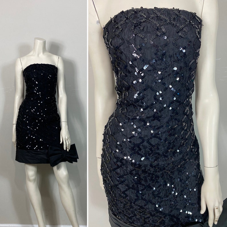 May include: A black strapless sequined mini dress with a black bow at the waist.