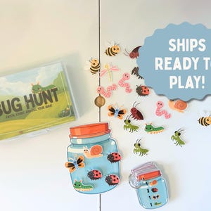 May include: A children's game set with the words "BUG HUNT" on the box. The set includes a clear plastic container, illustrated bug cutouts, and jar-shaped cards. The text "SHIPS READY TO PLAY!" is on a blue cloud-shaped sign.