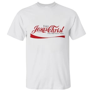 May include: White t-shirt featuring a red graphic with the words "Enjoy Jesus Christ Thou Shalt Never Thirst". The design is in a stylized font, similar to a well-known brand.