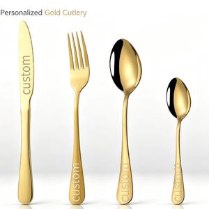 May include: A set of four gold-colored stainless steel cutlery pieces including a knife, fork, dinner spoon, and teaspoon. Each piece features the word custom engraved on the handle or blade. The text Personalized Gold Cutlery is visible.