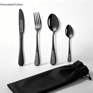 May include: A set of four matte black stainless steel cutlery pieces including a knife, fork, large spoon, and small spoon, each engraved with the word custom. A black drawstring pouch is included with the set of personalized cutlery.