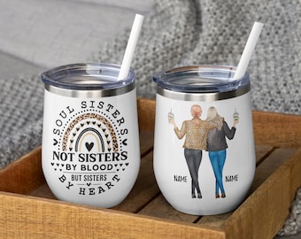 Puede incluir: Dos vasos blancos de acero inoxidable con tapas transparentes y pajitas blancas. Uno presenta un arcoíris con estampado de leopardo y el texto Soul Sisters Not Sisters By Blood But Sisters By Heart. El otro muestra dos figuras con nombres.