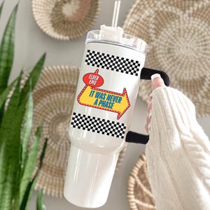 May include: White stainless steel tumbler with a black and white checkered design and a yellow arrow with the text "It was never a phase" and a red circle with the text "Elder Emo".