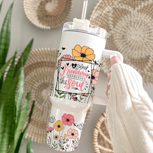 May include: White stainless steel tumbler with a floral design and the text "A Sweet Friendship Refreshes the Soul".