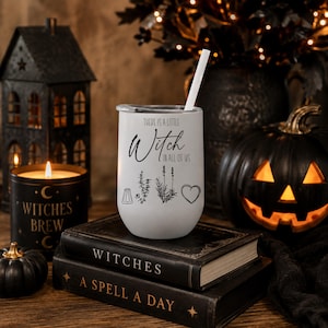 May include: A white stainless steel tumbler with a clear lid and a white straw. The tumbler features black text that reads "There is a little Witch in all of us" above illustrations of a salt shaker, a sprig of herbs, a lavender stalk, and a heart.