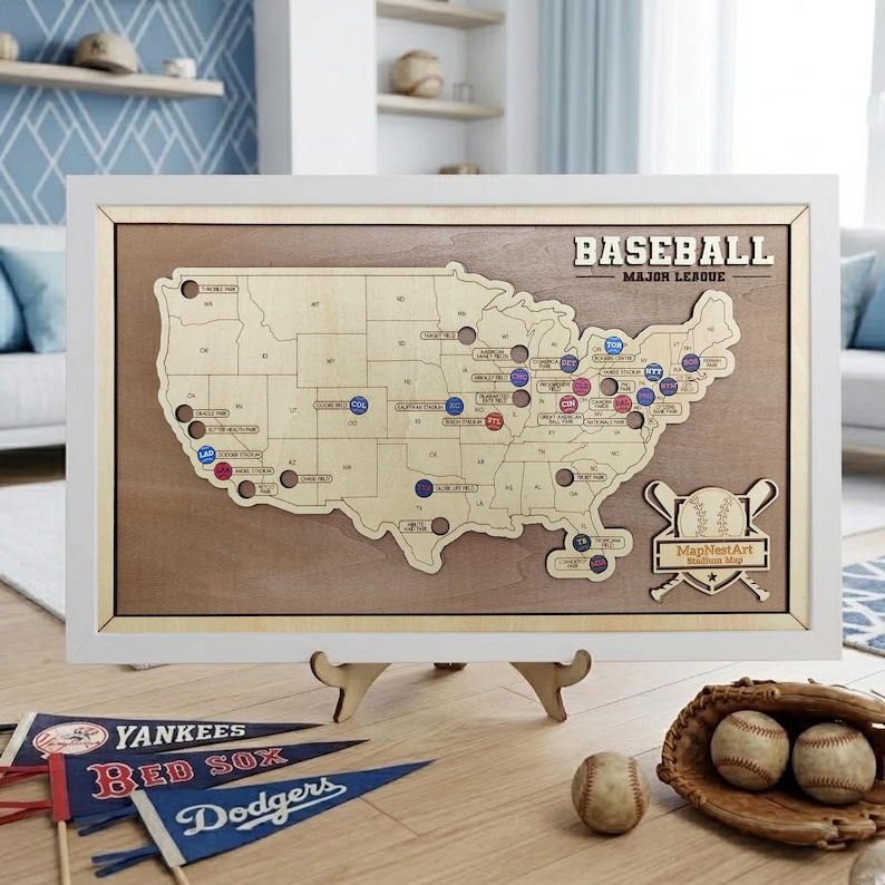 May include: A framed wooden baseball stadium map of the United States with team markers. The map is displayed on a wooden stand, with baseball pennants and baseballs nearby. The frame is white, and the map has the text "BASEBALL MAJOR LEAGUE".