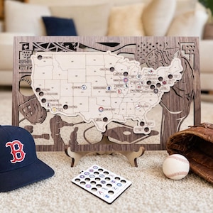 May include: A wooden baseball-themed map of the United States with cut-out details and team logos. Includes a navy blue baseball cap with a red "B" logo, a baseball, a baseball glove, and a set of team logo tokens.