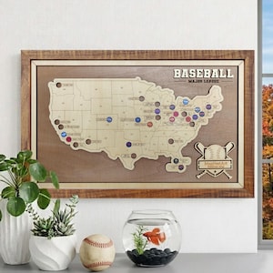 May include: A wooden map of the United States with baseball stadium locations marked. The map is framed in a brown wooden frame and features the text "BASEBALL MAJOR LEAGUE". A baseball and a baseball are also in the image.