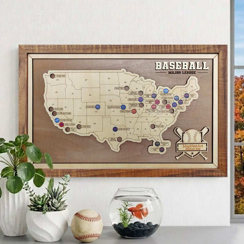 May include: A wooden map of the United States with baseball stadium locations marked. The map is framed in a brown wooden frame and features the text "BASEBALL MAJOR LEAGUE". A baseball and a baseball are also in the image.