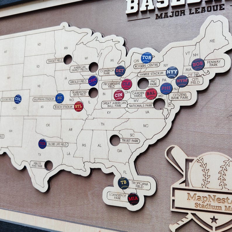 May include: A wooden map of the United States with baseball stadium markers. The map is light brown with stadium names and team logos. The words "BASEBALL MAJOR LEAGUE" are at the top.