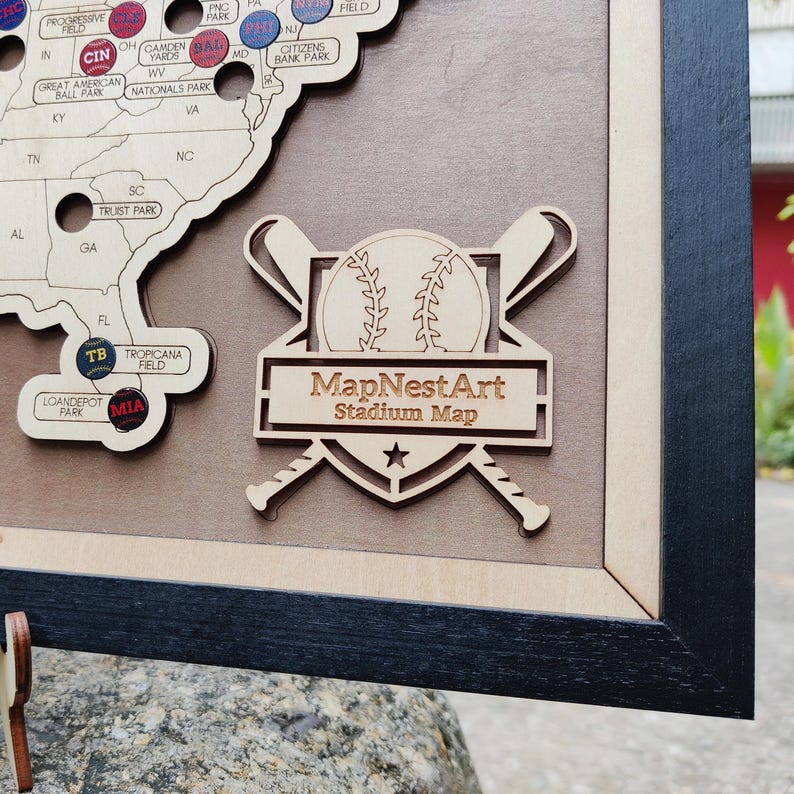 May include: Wooden baseball stadium map with a black frame. The map features a baseball graphic with crossed bats and the text "MapNestArt Stadium Map". The map includes stadium locations across the United States.