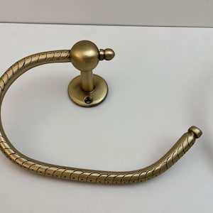 K&ouml;nnte beinhalten: Zwei antike Handtuchringe aus Messing. Jeder Ring hat ein kreisf&ouml;rmiges Design mit einer seilartigen Textur. Die Ringe sind auf einer runden Basis mit einem zentralen Pfosten und einer dekorativen Kugel befestigt. Badezimmerdekoration.