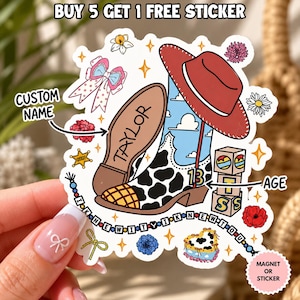 May include: A die-cut sticker featuring a cow-print cowboy boot with a blue sky and cloud pattern, a red cowboy hat, a pink bow, flowers, a sheriff star, and alphabet blocks. The text includes "TAYLOR", "13", "I KNEW IT", and "BUY 5 GET 1 FREE STICKER".