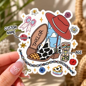 May include: A die-cut sticker featuring a cow-print cowboy boot, a red hat, and a string of beads with the text I KNEW IT. The boot displays the name TAYLOR and the number 13. Decorative elements include flowers, a bow, and blocks labelled AGE.
