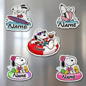 May include: A collection of Snoopy-themed stickers in a summer vacation theme. Snoopy is depicted surfing, floating in a tube, and relaxing with a coconut drink. Each sticker has the word "Name" on it.