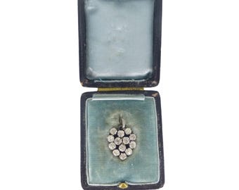 May include: A vintage pendant with a cluster of small, round, clear gemstones, presented in an open, black jewelry box with a light blue velvet interior. The pendant is suspended from a delicate chain.