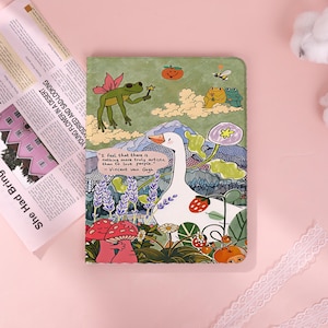 Op de afbeelding: Een groen notitieboek met een grillige illustratie met een witte gans, kikkers, paddenstoelen en bloemen. De omslag bevat een citaat van Vincent van Gogh. Het notitieboek is versierd met een kleurrijk, cartoonachtig ontwerp.
