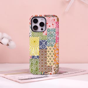 May include: A smartphone case featuring a vibrant patchwork design of various geometric, floral, and sunburst patterns in shades of yellow, green, blue, orange, and pink. The case has a rectangular cutout for a triple-lens camera system.