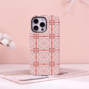 May include: A smartphone case featuring a repeating grid pattern of dark brown filigree swirls and small hearts on a light pink background, separated by thin red vertical and horizontal lines, with a black camera cutout at the top left corner.