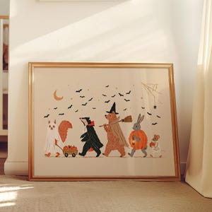 May include: A framed horizontal art print featuring a group of woodland animals dressed in Halloween costumes, including a ghost, a vampire, a witch, a pumpkin, and a skeleton, walking under a crescent moon and black bats.